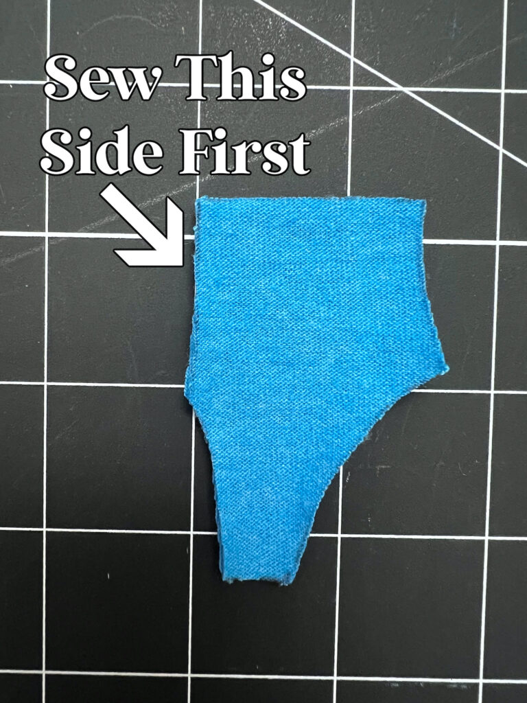 A piece of blue fabric on a grid background with an arrow and text indicating which side to sew first.