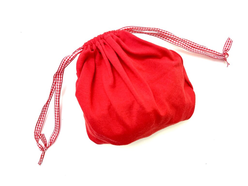 A red drawstring t-shirt bag with red and white checkered ties, displayed on a white background.