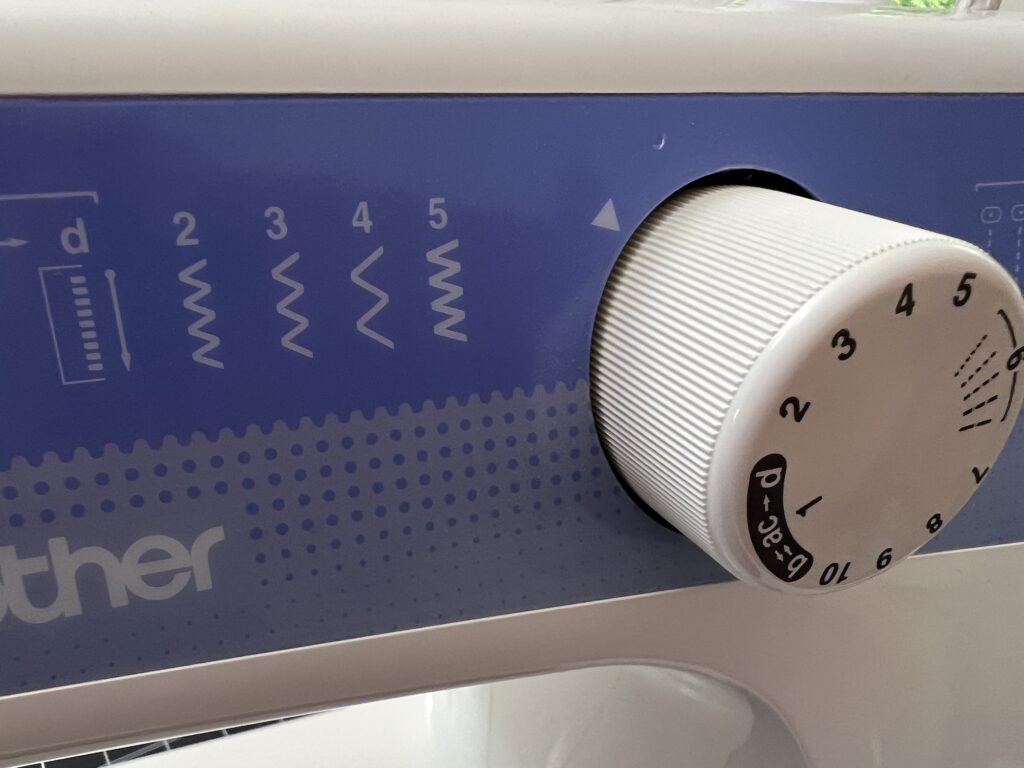 Close-up of a sewing machine stitch selector dial set to option 4, with five stitch pattern icons visible on a blue background—perfect for crafting your next t-shirt bag.