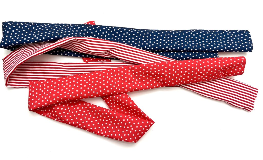 Three fabric belts are shown: one is blue with white stars, one is red with white stars, and one is red and white striped, all arranged on a white background.