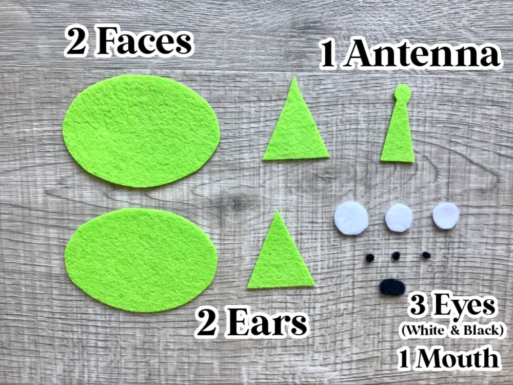 Green felt pieces for a craft project: 2 ovals labeled "Faces," 2 triangles labeled "Ears," 1 triangle labeled "Antenna," and various small circles labeled "Eyes" and "Mouth.