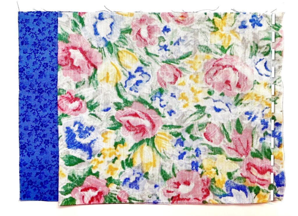 A piece of fabric featuring a blue floral strip on the left and a larger section with multicolored flowers, including pink, yellow, and blue, on a white background.