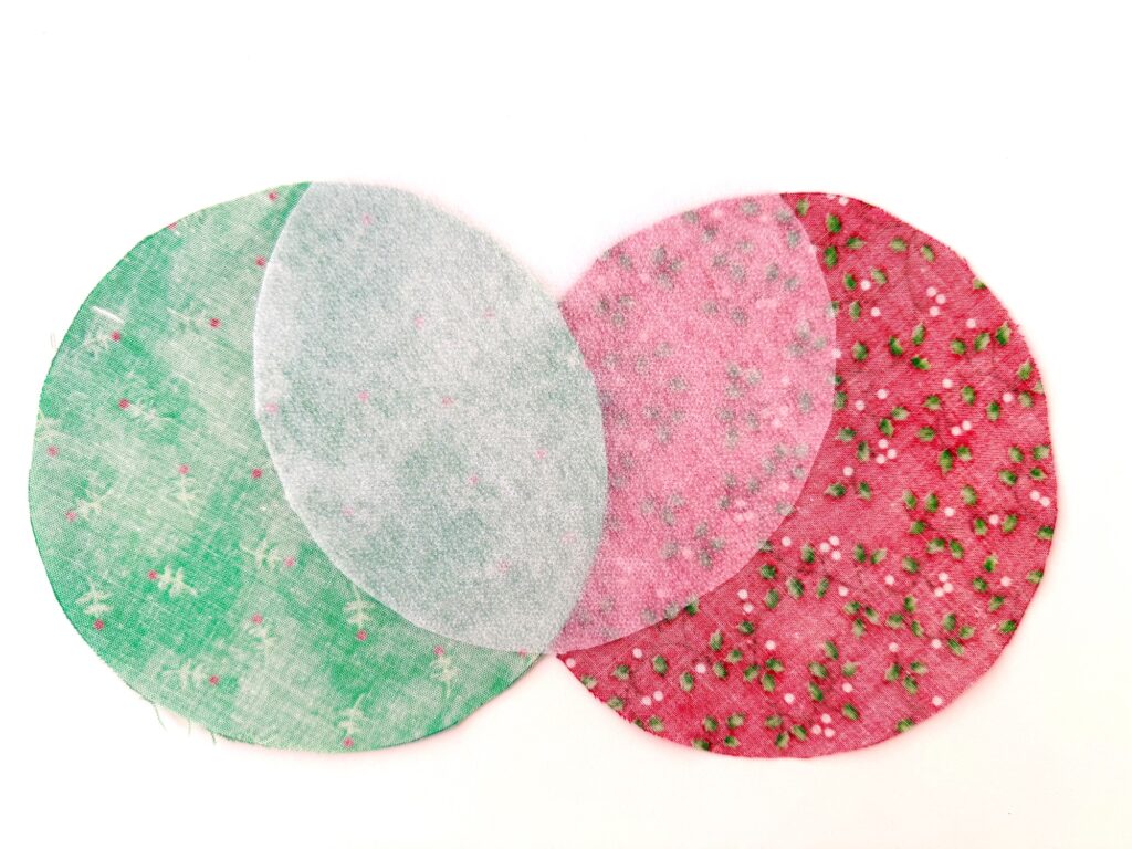 Three overlapping fabric circles in green, light pink, and red patterns are arranged on a white background.