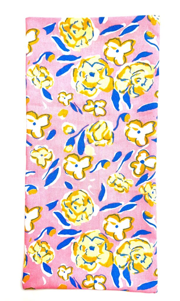 Rectangular fabric trivet with a pink background, featuring a yellow, white, and blue abstract floral pattern.