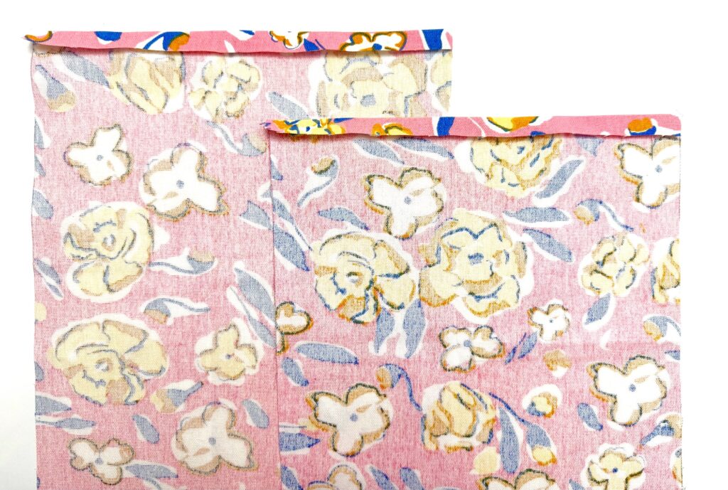 Two pink paper bags with a white, yellow, and blue floral pattern are shown overlapping each other against a white background, perfect for gifting or storing a small trivet in style.