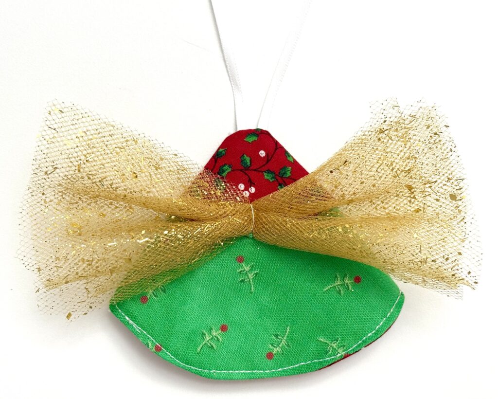 A handmade Christmas ornament shaped like an angel with a green fabric body, red head, and gold mesh wings, hanging by a white ribbon.