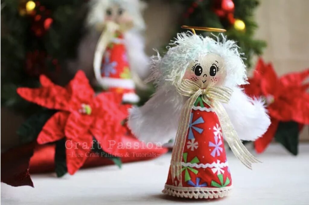 A handmade angel ornament with a red patterned dress and white wings is displayed in front of festive poinsettias and greenery.