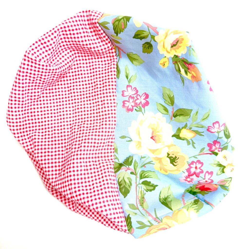 A charming tissue box cover crafted as a fabric pouch, with one side in red gingham and the other adorned with a blue floral print.