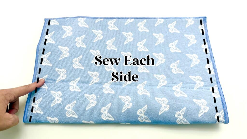 A blue fabric with a white butterfly pattern is folded in half; a finger points to one edge. Text reads "Sew Each Side" with dashed lines along the left and right edges.