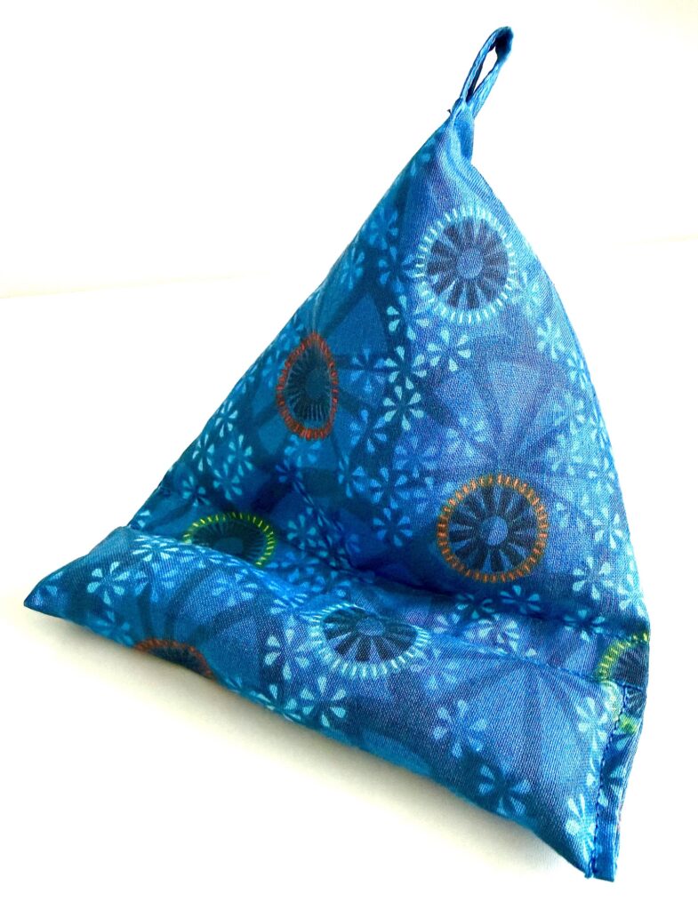 A blue fabric phone or tablet stand with a geometric circular pattern, shaped like a triangle and featuring a small loop at the top.