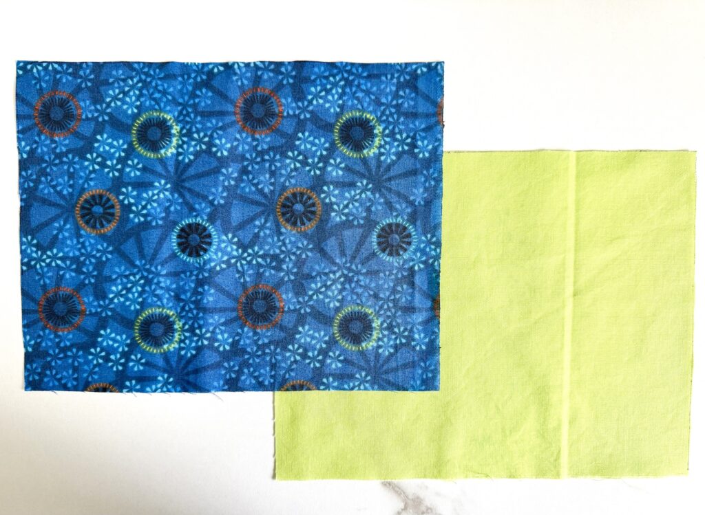 Two fabric rectangles are shown side by side on a white surface, one with a blue geometric pattern and one solid yellow-green.