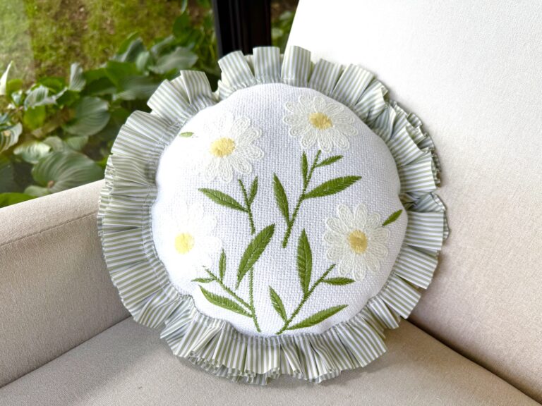 a handmade throw pillow made from daisy placemats with a green and white striped ruffle edge