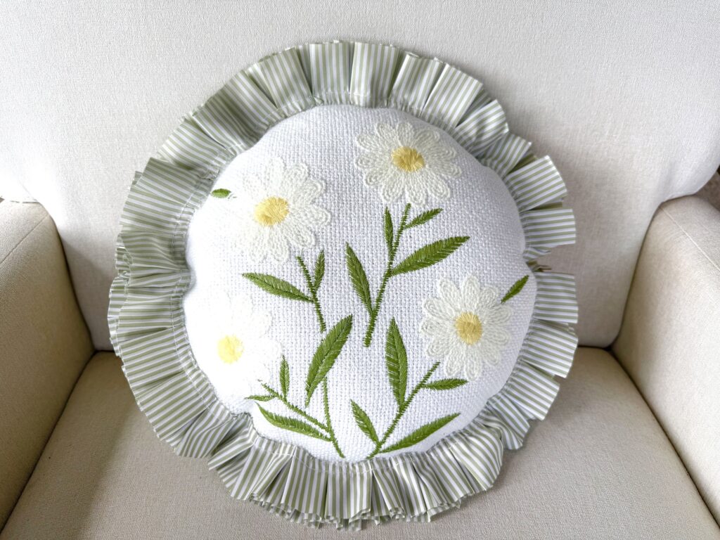 a handmade throw pillow made from daisy placemats with a green and white striped ruffle edge