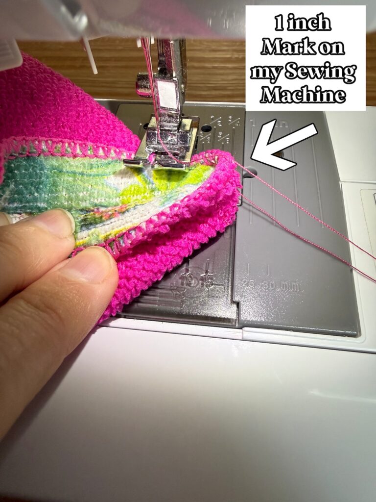 A close-up of fabric being stitched under a sewing machine needle, with text labeling the 1-inch mark on the machine’s needle plate.