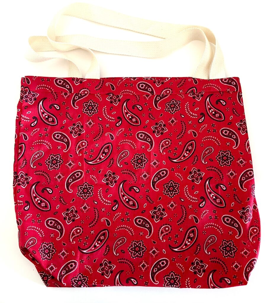Red tote bag with white handles, featuring a black and white paisley pattern on the fabric.
