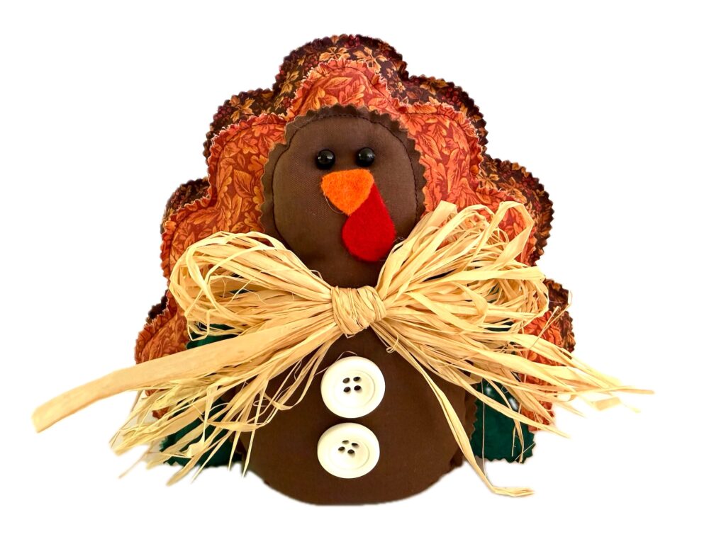 Fabric turkey decoration with a raffia bow and two white buttons on its chest.